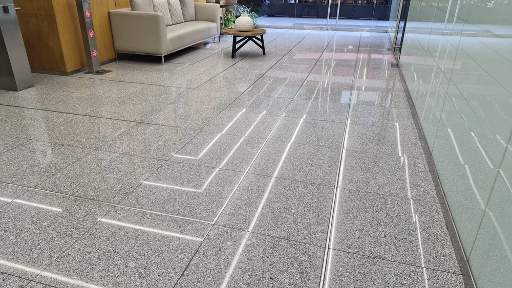 Piso de granito pulido con brillo espejo en recepción de oficinas
